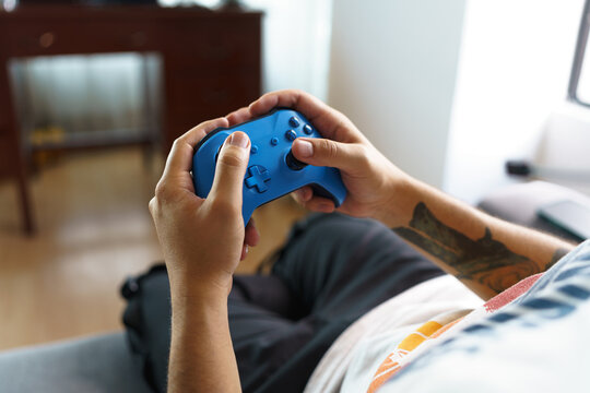 hands holding and playing with a blue video game controller, details of joystick and buttons, gamer having fun, technology