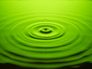 Closeup of water drop falling down on green

