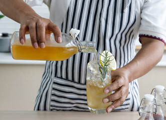 Hand of Man pouring Kombucha tea into a glass, Kombucha fermented drink, bacteria and yeast, ...