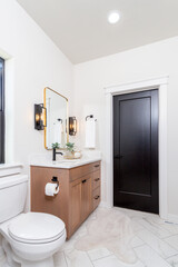 A modern farmhouse bathroom with wood cabinets, quartz countertops and black pulls.