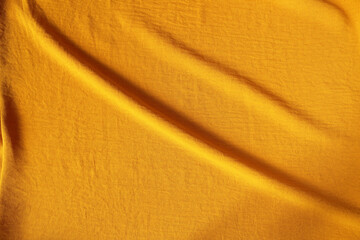 Orange ocher crumpled fabric for creative background. Copy space. Vivid textile for wallpaper or design