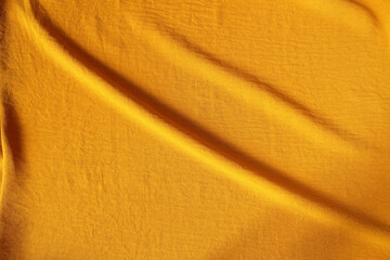 Orange ocher crumpled fabric for creative background. Copy space. Vivid textile for wallpaper or...