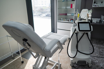 Empty beautician office with white couch and photorejuvenation machine. 