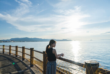 夕暮れの海を散策する女性