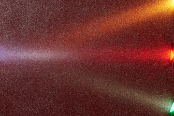 On a dark red rough background in fine grain, multi-colored rays converge at one point