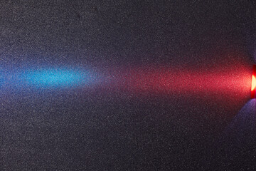 Red and blue transient bright gradient beam of light on dark purple grungy background