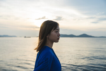 夕暮れの海にいる青いワンピースの女性