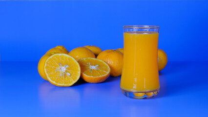 Close-up and vivid studio shot, a glass of orange juice, and a group of natural fresh oranges on a...