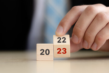 Beginning and start of the new year 2023. Preparation for happy new year ,new life, new business, plan, goals, strategy concept. Hand flips wooden cubes with  2022 to 2023 on smart background.