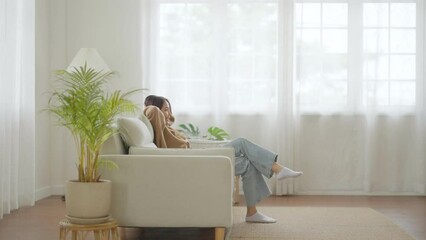 Asian woman sit down on couch. Happy female relax and resting on sofa in living room. Teenage girl smile and cheerful free time at house