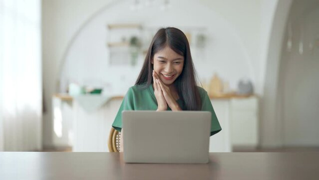 Funny euphoric young asian woman celebrating winning or getting ecommerce shopping offer on computer laptop. Excited happy girl winner looking at notebook celebrating success