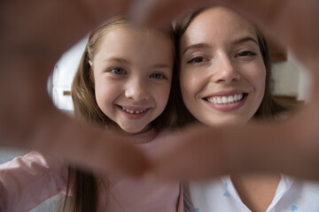 Cute faces of mom and daughter join fingers showing heart symbol, close up cropped shot. Happy Mothers Day, unconditional love, bloggers record video, family share sincere feelings, videocall concept