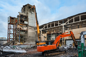 Disassembling of old industrial building by high excavator