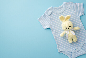 Baby boy concept. Top view photo of knitted bunny toy over blue bodysuit on isolated pastel blue background with copyspace