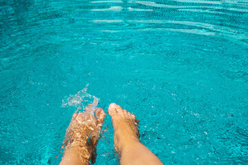 Female feet in blue water pool. Vacation and sport concept