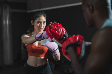 Asian fit female boxing training with her trainer at gym.Sportwoman  wearing boxing gloves exercise...