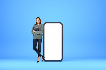 Woman with notebook near phone mockup display on blue background. Copy space