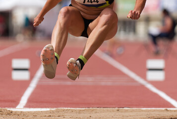 Female athlete performing a long jump during a competition at stadium