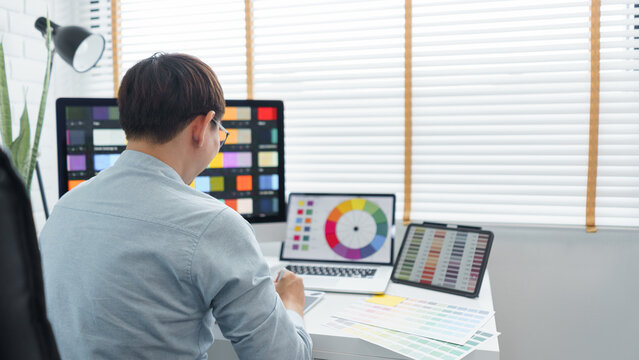 Creativity concept, Male graphic designer using tablet and looking color swatch samples on screen