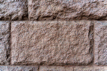 Texture. The wall is made of rectangular blocks of red granite.