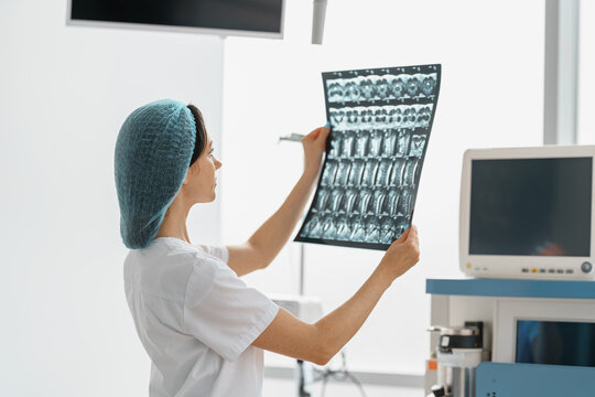 Nurse In Uniform Look On X-ray Or MRI Scan Of The Patient Spine In Operation Room