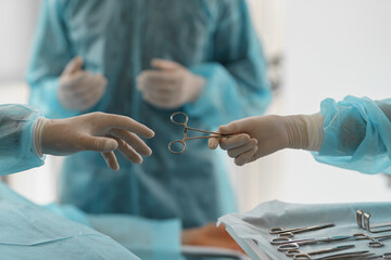 Assistant hands out instruments surgeon during surgery in the operating room - obrazy, fototapety, plakaty