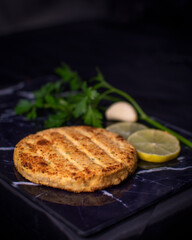 Burger made of soya and oats with parsley, garlic, lemon and a black background.