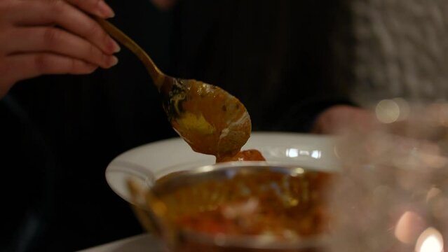 A spoon of indian food onto a plate