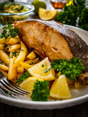 Fish dish - fried halibut with French fries and lemon on wooden table
