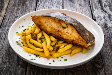 Fish dish - fried halibut with French fries and lemon on wooden table
