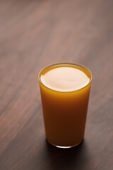 orange, pumpkin and carrot mixed juice in tumbler glass on walnut table