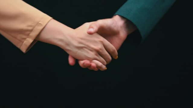 Two businessmen shake hands on a black background, good deal. Handshake of people in jackets. Business agreement on business. Greeting of two business people.