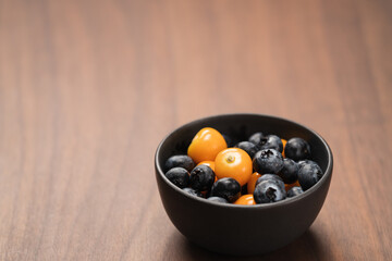 Blueberries with physalis in a bowl on wood table