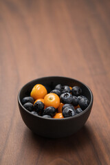 Blueberries with physalis in a bowl on wood table