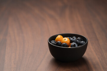Blueberries with physalis in a bowl on wood table
