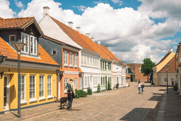 Beautiful old traditional houses in Odense old town, Denmark, Europe with people walking with dog...