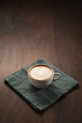 Fresh flat white with latte art in ceramic cup on wood table