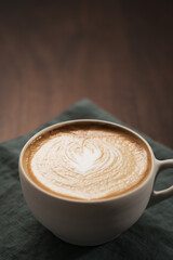 Fresh flat white with latte art in ceramic cup on wood table