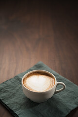 Fresh flat white with latte art in ceramic cup on wood table