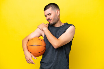 Young caucasian basketball player man isolated on yellow background suffering from pain in shoulder...