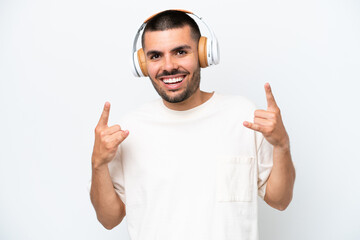 Young caucasian man isolated on white background listening music making rock gesture