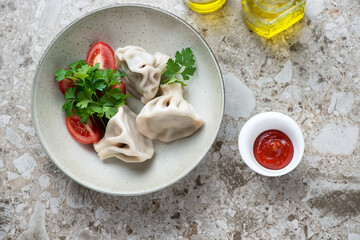 Plate of georgian khinkali dumplings with meat stuffing, top view on a brown stone background, horizontal shot
