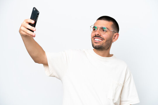 Young caucasian man isolated on white background making a selfie with mobile phone