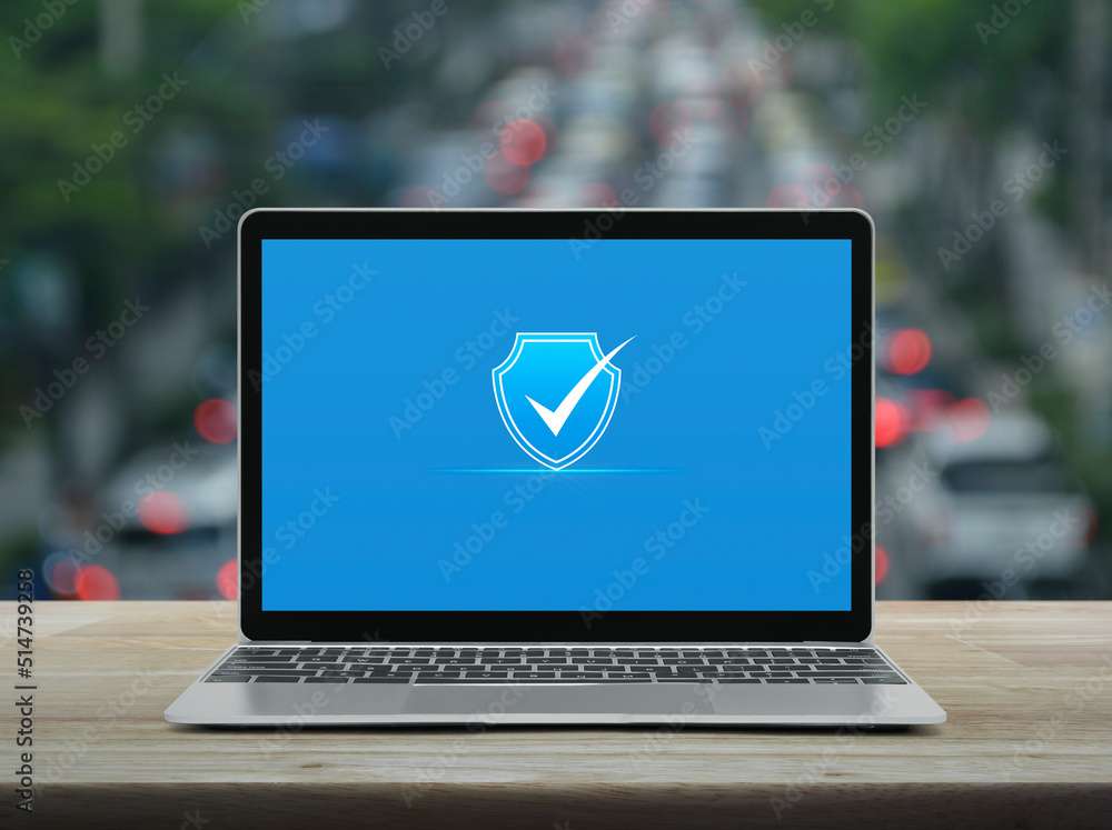 Aufkleber security shield with check mark icon on modern laptop computer monitor screen on wooden table over b
