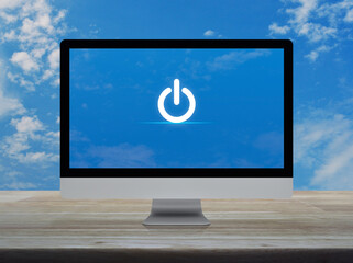 Power button icon on desktop modern computer monitor screen on wooden table over blue sky with...