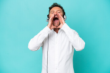 Telemarketer caucasian man working with a headset isolated on blue background shouting and announcing something