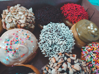 assorted donuts with chocolate frosted, pink glazed and sprinkles donuts.