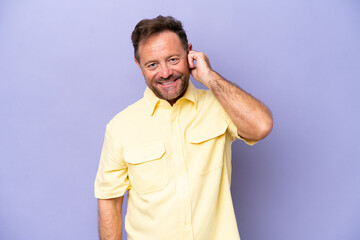 Middle age caucasian man isolated on purple background laughing