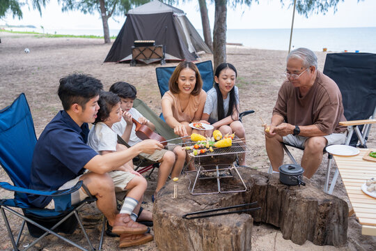 Happy Asian Family Having Barbecue Together. Cooking Grilled Bbq For Dinner During Camping On Summer Beach.