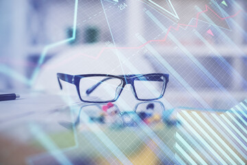 Financial chart hologram with glasses on the table background. Concept of business. Double exposure.